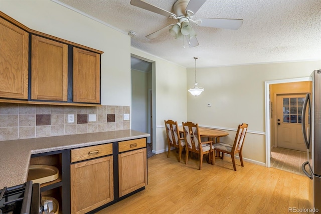 39045 Big Springs Rd, Rush, CO 80833 - kitchen with freestanding refrigerator, brown cabinets, light wood finished floors, a textured ceiling, and decorative backsplash