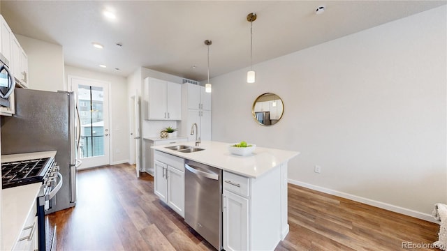 kitchen with hardwood / wood-style floors, a kitchen island with sink, sink, appliances with stainless steel finishes, and white cabinetry