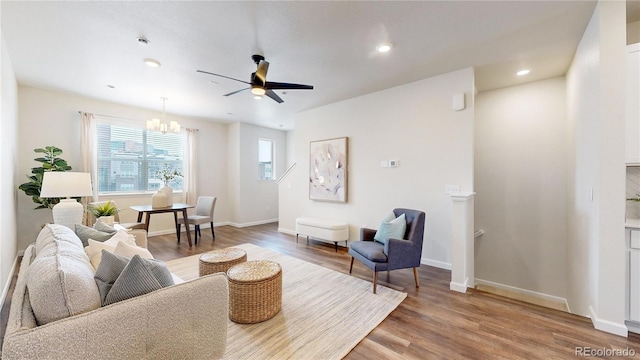 living room featuring hardwood / wood-style floors and ceiling fan with notable chandelier