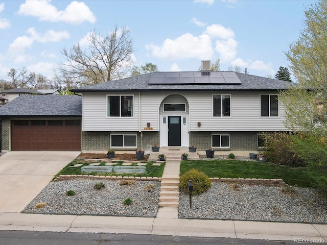 11165 W 58th Ave, Arvada, CO 80002 - raised ranch featuring a garage, brick siding, roof mounted solar panels, concrete driveway, and a front lawn