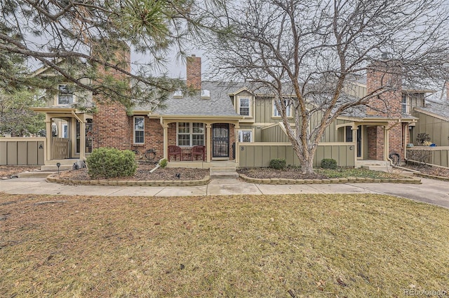 view of front of house featuring a front yard, brick siding, fence, and a chimney