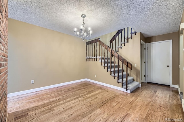 interior space with light wood finished floors, stairway, an inviting chandelier, a textured ceiling, and baseboards