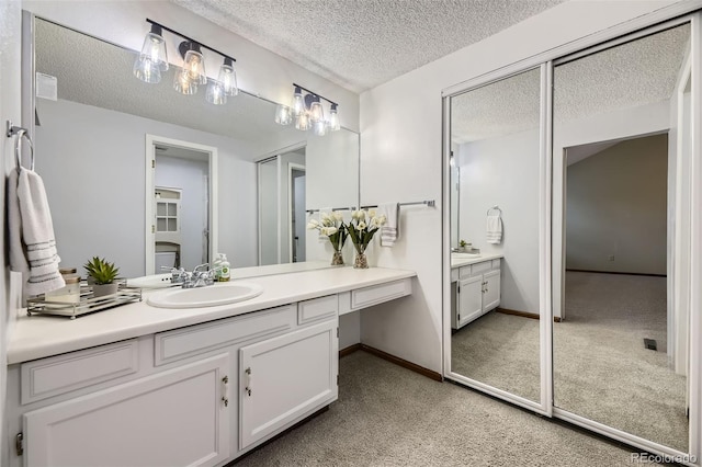 bathroom with a textured ceiling, carpet flooring, vanity, and baseboards