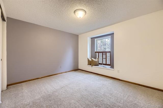 spare room featuring light carpet, a textured ceiling, and baseboards