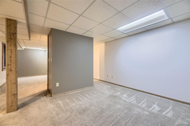 finished below grade area featuring carpet floors, a paneled ceiling, and baseboards