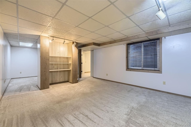 finished below grade area featuring baseboards, light carpet, and a drop ceiling