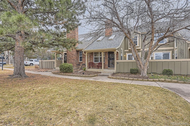 7721 S Curtice Way Unit B, Littleton, CO 80120 - tudor home featuring a chimney, a shingled roof, brick siding, and a porch