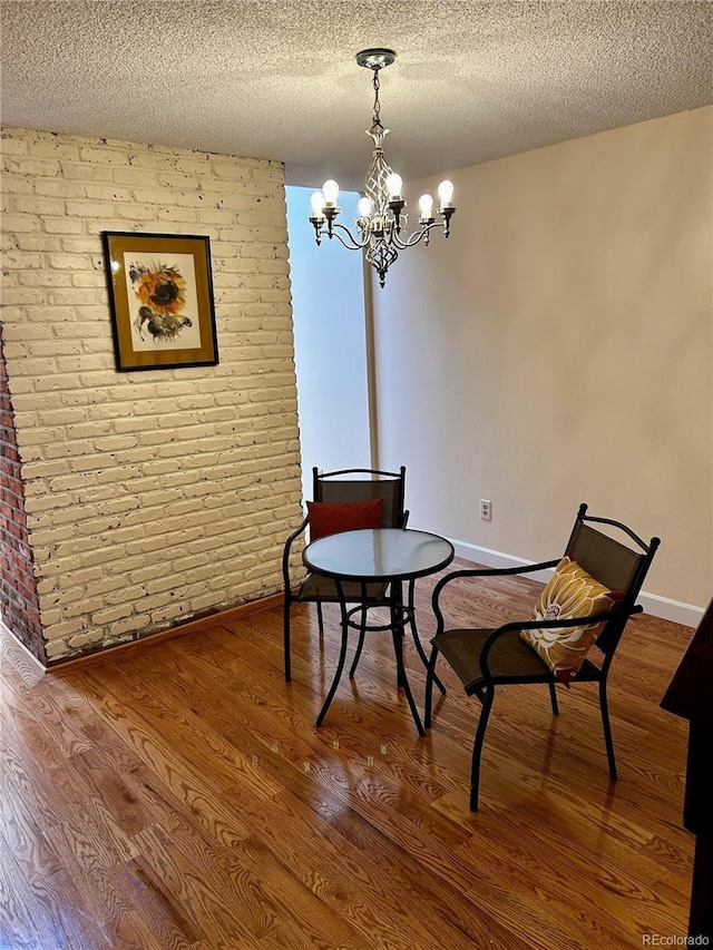 7721 S Curtice Way Unit B, Littleton, CO 80120 - living area featuring a textured ceiling, brick wall, a chandelier, and wood finished floors