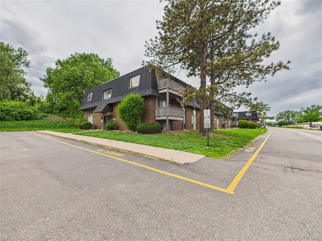 190 E Highline Cir Unit 302, Centennial, CO 80122 - view of front of home featuring mansard roof, a shingled roof, brick siding, a front yard, and a balcony