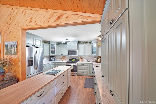 kitchen with tasteful backsplash, wooden counters, wooden walls, appliances with stainless steel finishes, and light wood-type flooring