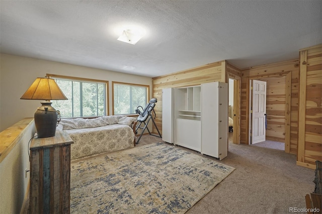 carpeted bedroom featuring wood walls and a textured ceiling