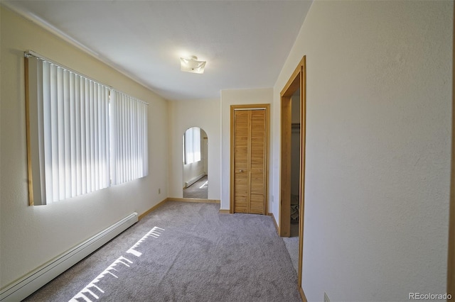 interior space featuring a closet, light colored carpet, and a baseboard heating unit