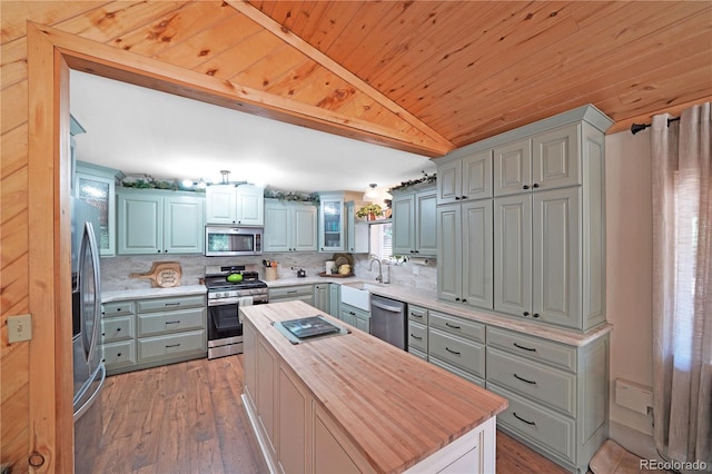 kitchen featuring gray cabinets, wood counters, appliances with stainless steel finishes, hardwood / wood-style flooring, and a center island