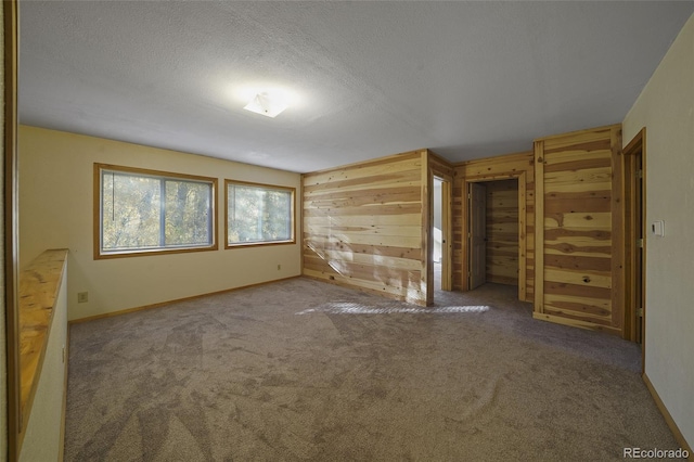 unfurnished bedroom with a textured ceiling, wooden walls, and carpet flooring