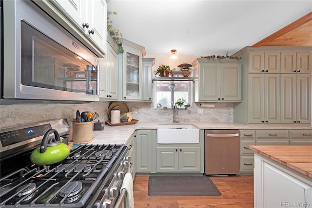 kitchen featuring sink, appliances with stainless steel finishes, light hardwood / wood-style floors, and decorative backsplash