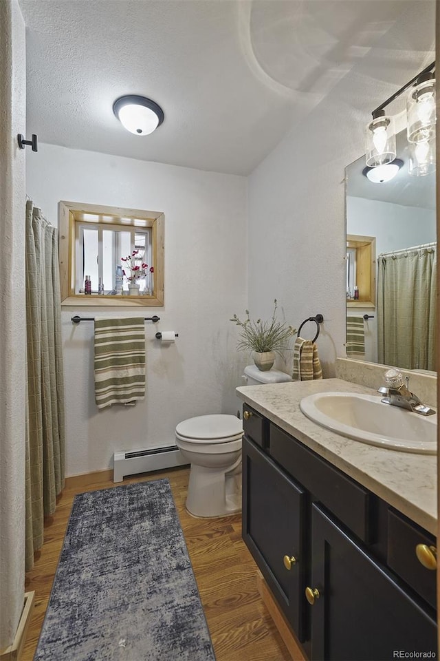 bathroom with vanity, a textured ceiling, hardwood / wood-style flooring, a baseboard radiator, and toilet