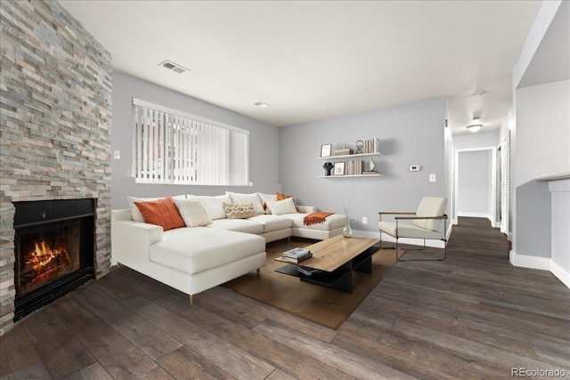 living room with dark wood-type flooring and a stone fireplace