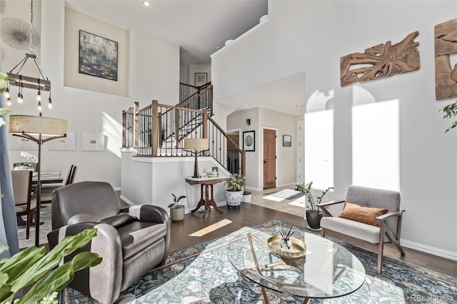 living room with baseboards, a high ceiling, stairway, and wood finished floors