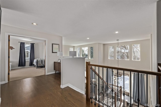 corridor with dark wood-style floors, recessed lighting, baseboards, and an upstairs landing