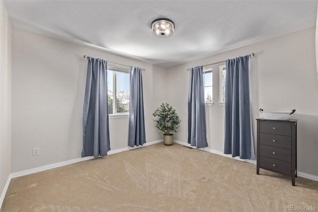 spare room featuring carpet flooring, a wealth of natural light, and baseboards