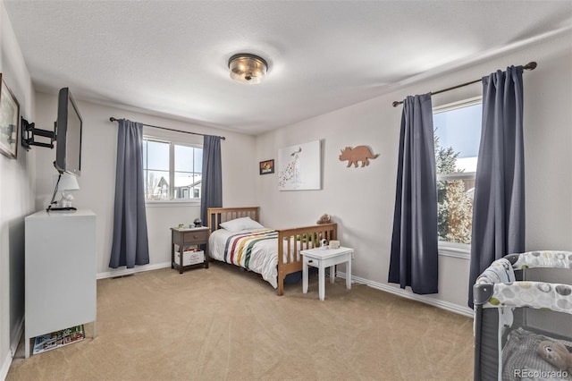 bedroom with light carpet, visible vents, baseboards, and a textured ceiling