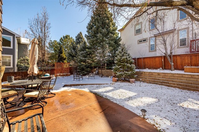 snow covered patio featuring outdoor dining space and a fenced backyard