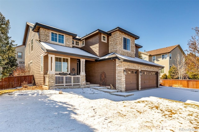 view of front of home with fence, driveway, a porch, a garage, and stone siding