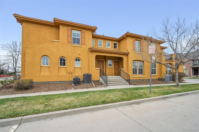 back of property with a tiled roof, cooling unit, and stucco siding