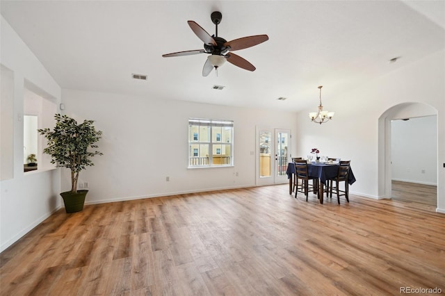 living room featuring visible vents, light wood finished floors, arched walkways, and ceiling fan with notable chandelier