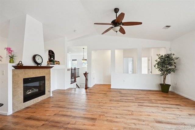 unfurnished living room featuring lofted ceiling, a fireplace, visible vents, ceiling fan, and wood finished floors