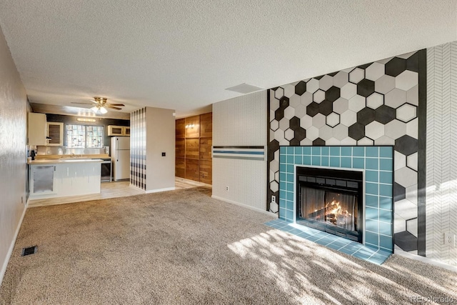 unfurnished living room with carpet flooring, a textured ceiling, a fireplace, and visible vents