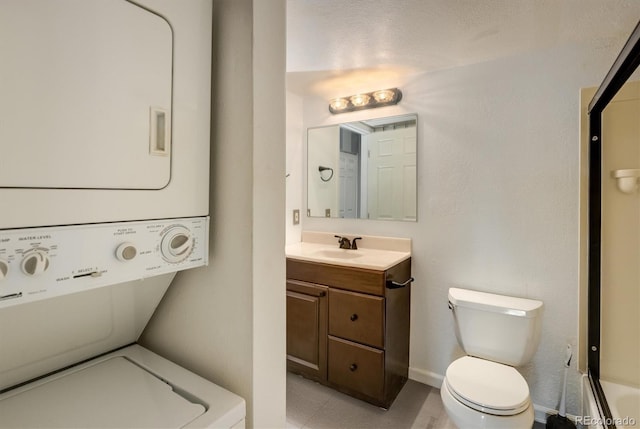 full bath with toilet, vanity, baseboards, and stacked washing maching and dryer