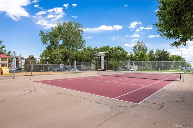 view of tennis court featuring community basketball court, fence, and playground community