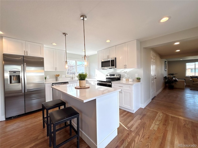 kitchen with a kitchen bar, white cabinetry, stainless steel appliances, and light wood-type flooring