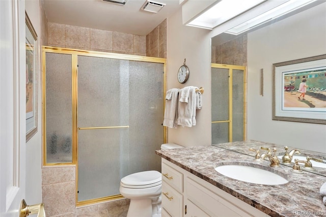 bathroom with a skylight, tile patterned flooring, vanity, an enclosed shower, and toilet