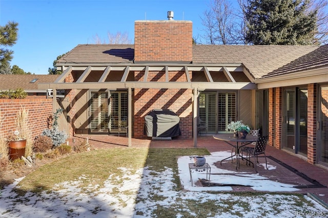 snow covered back of property featuring a patio area