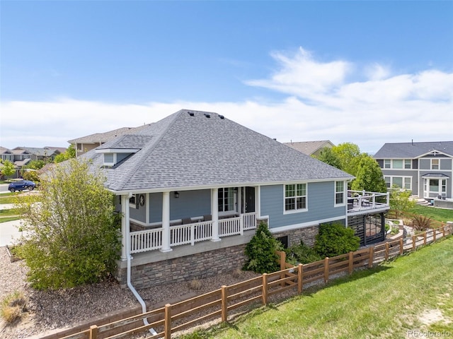 rear view of property featuring roof with shingles, a porch, and fence