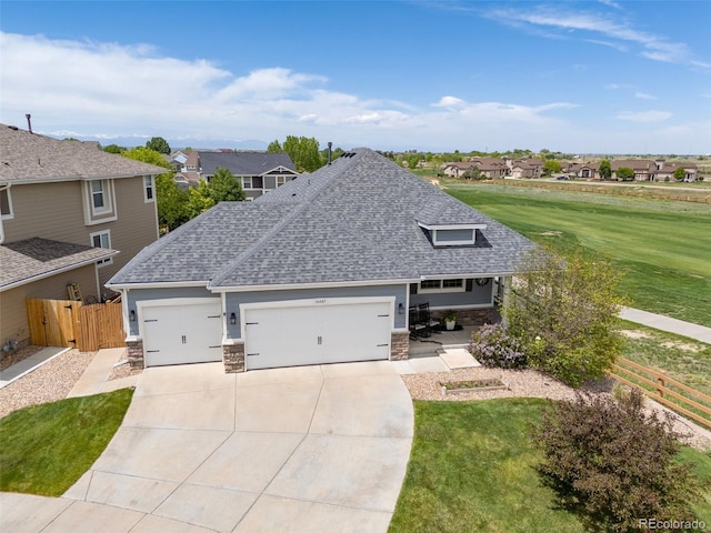 view of front facade with stone siding, an attached garage, a shingled roof, driveway, and a residential view