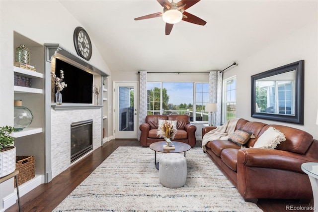 living area featuring a fireplace, a ceiling fan, built in features, lofted ceiling, and dark wood-type flooring