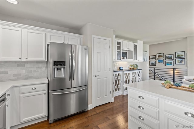 kitchen featuring appliances with stainless steel finishes, dark wood-style floors, white cabinets, glass insert cabinets, and backsplash