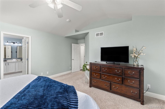 bedroom with lofted ceiling, light colored carpet, baseboards, ensuite bath, and ceiling fan