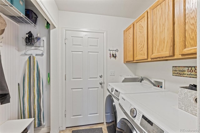 clothes washing area featuring cabinet space and washer and dryer