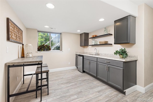 indoor wet bar with baseboards, light wood-type flooring, dishwasher, and recessed lighting