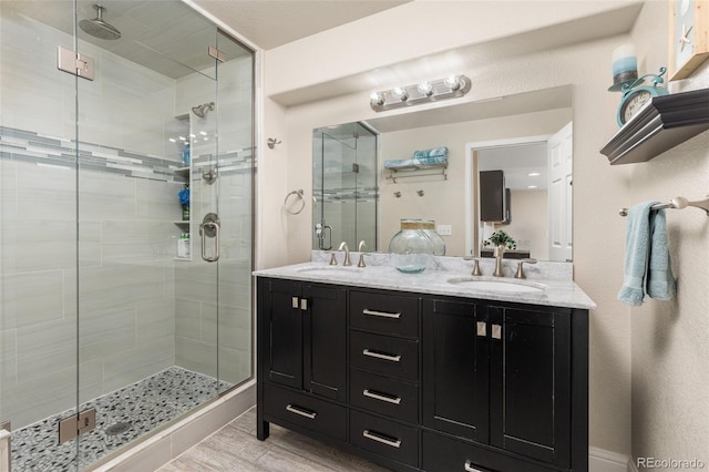 full bathroom with a shower stall, wood finished floors, and double vanity