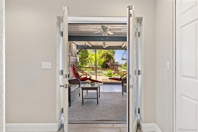 doorway with baseboards and ceiling fan