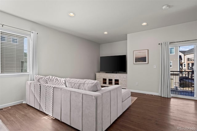 living room with a wealth of natural light and dark wood-type flooring