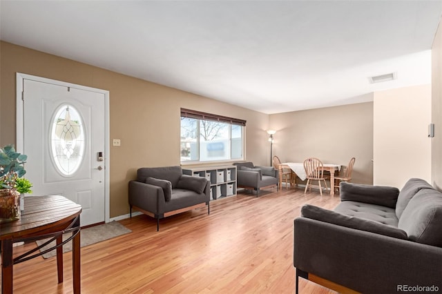 living area featuring baseboards, visible vents, and light wood-style floors