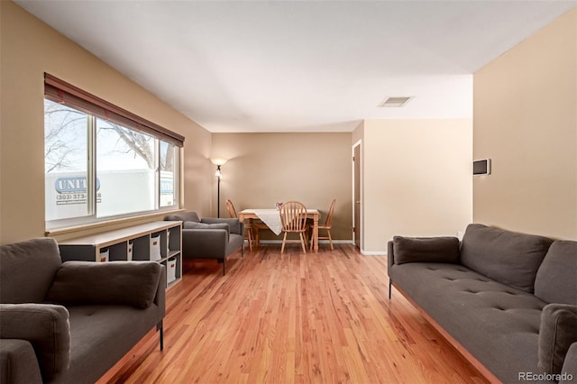 living area with light wood-style floors, baseboards, and visible vents