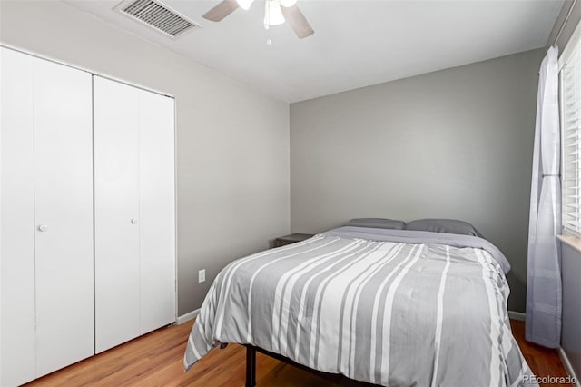 bedroom with a closet, visible vents, ceiling fan, wood finished floors, and baseboards