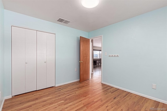 unfurnished bedroom with light wood finished floors, a closet, visible vents, and baseboards